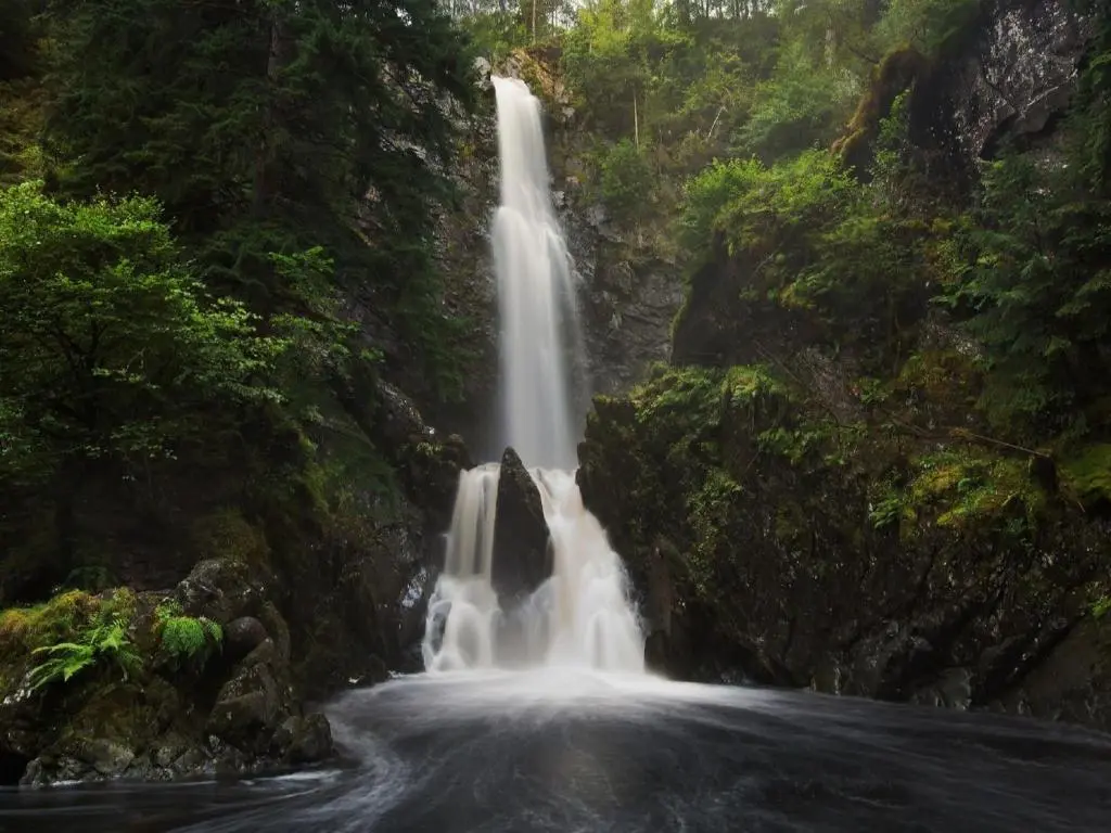 a waterfall in the middle of a forest at Guisachan Lodge at Lochletter Lodges in Drumnadrochit