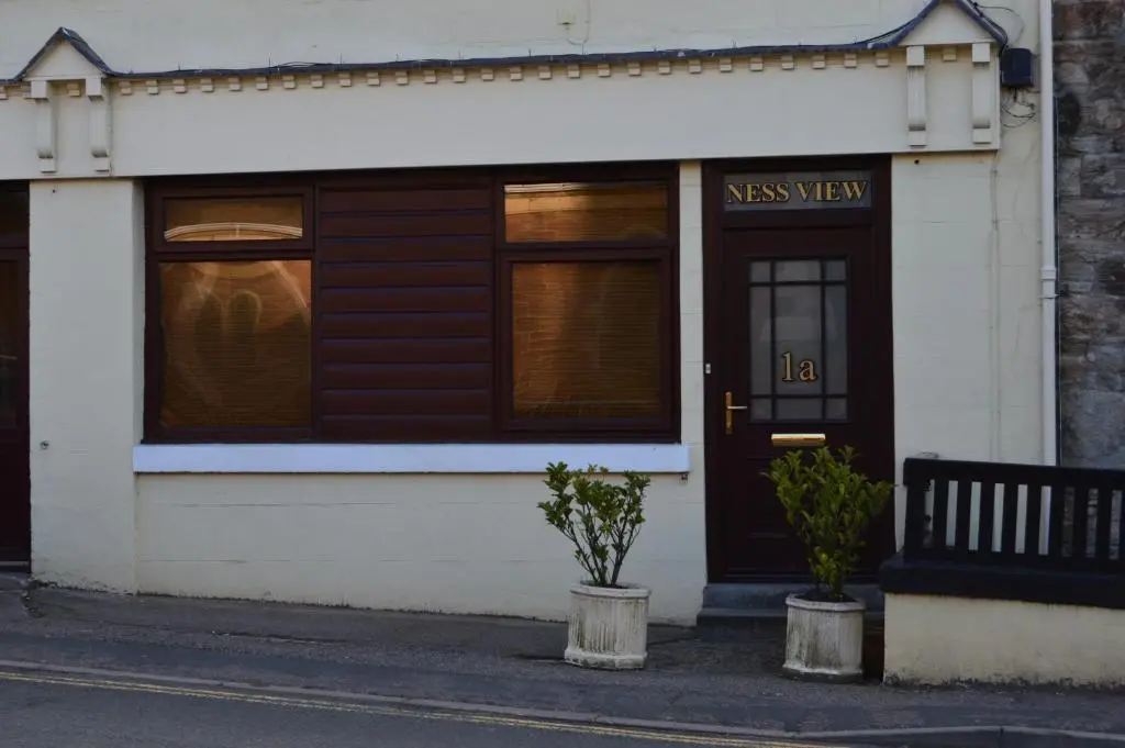 a house with a black door and a sign on it at Ness View Apartment in Inverness