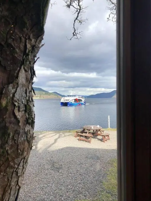 a view of a lake with a picnic table and a boat at 3 BR Luxury Apt at Highland Club - Fort Augustus in Fort Augustus