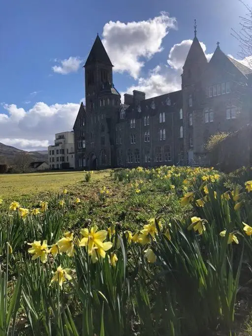 a large building with a field of flowers in front of it at 3 BR Luxury Apt at Highland Club - Fort Augustus in Fort Augustus