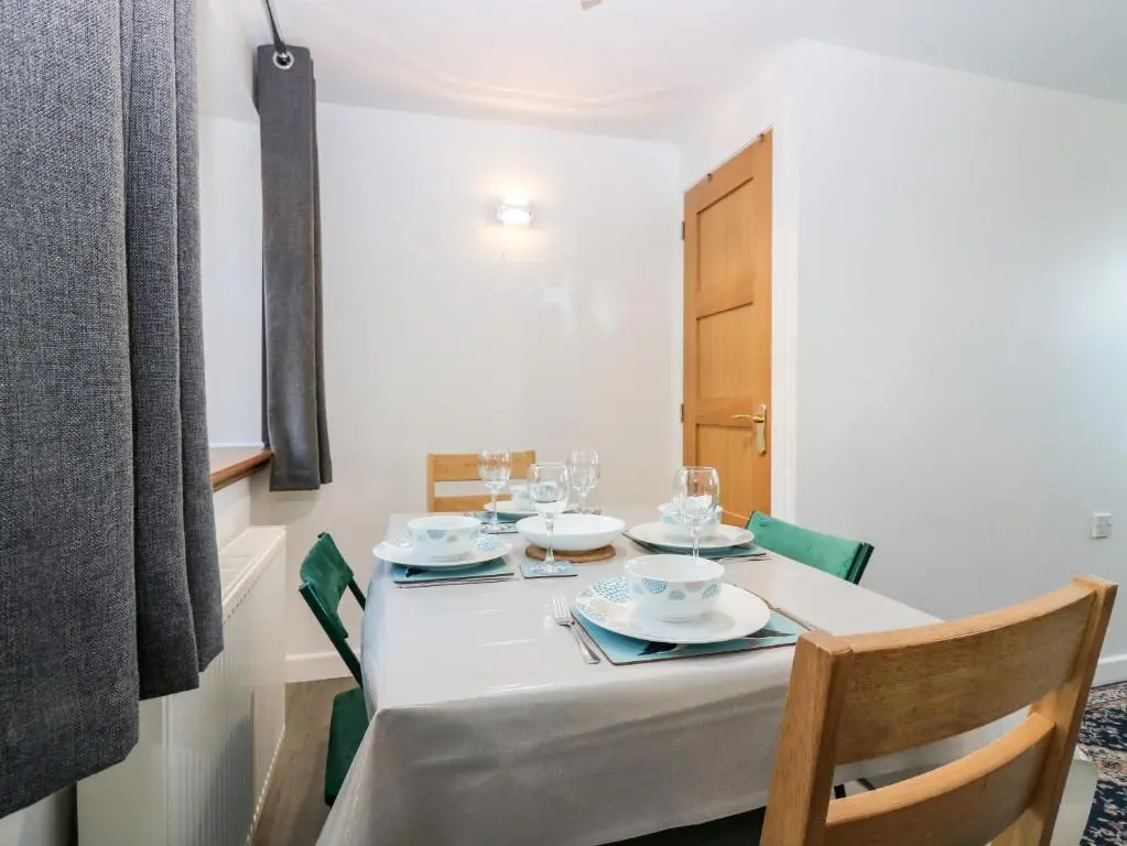 a dining room table with a white table cloth and chairs at Dolphin Cottage in Banff