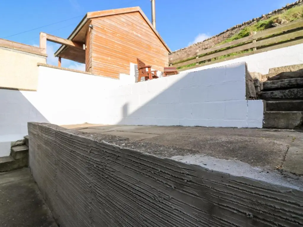 a white retaining wall next to a building at Dolphin Cottage in Banff