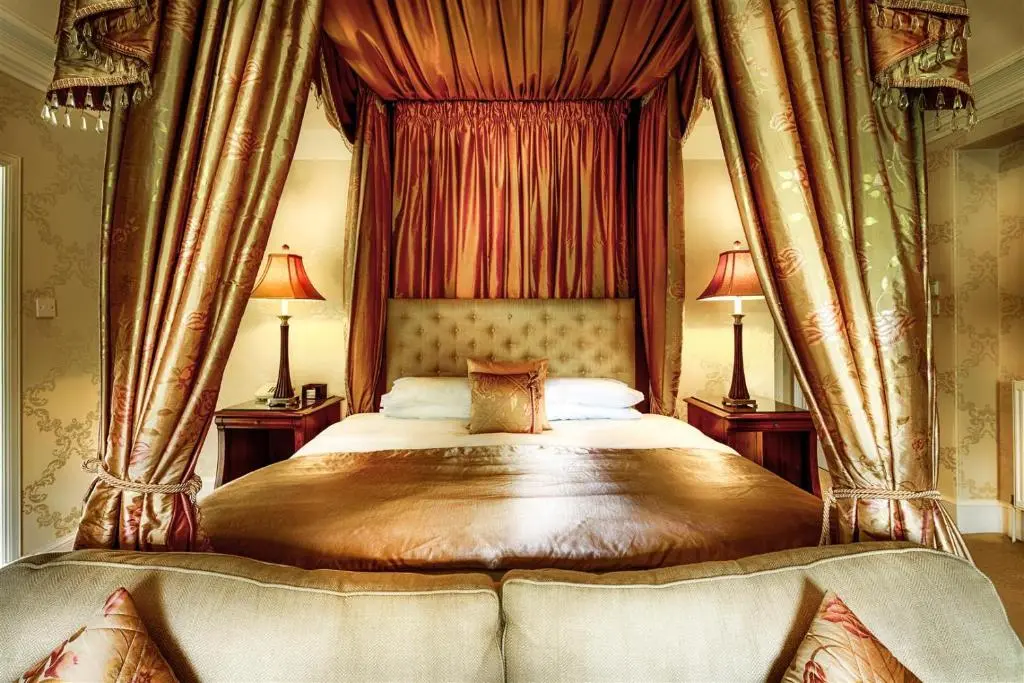 a bedroom with a canopy bed with two lamps at Mansion House Hotel in Elgin