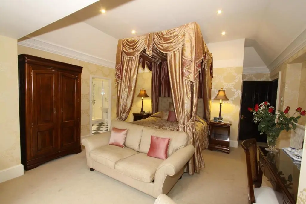 a bedroom with a canopy bed with pink pillows at Mansion House Hotel in Elgin