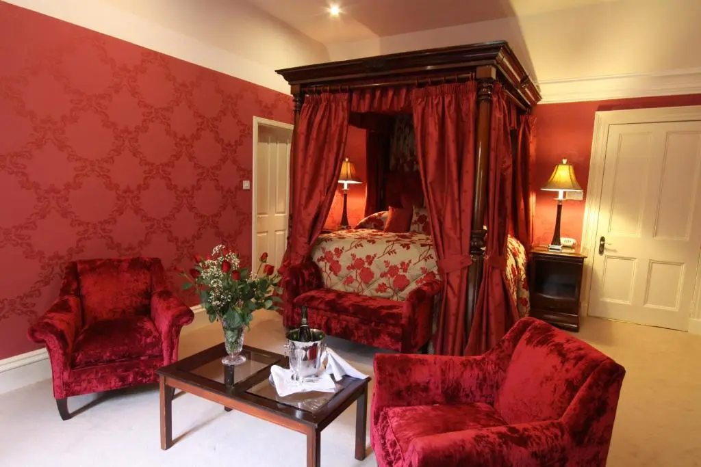 a bedroom with a bed and two chairs and a table at Mansion House Hotel in Elgin