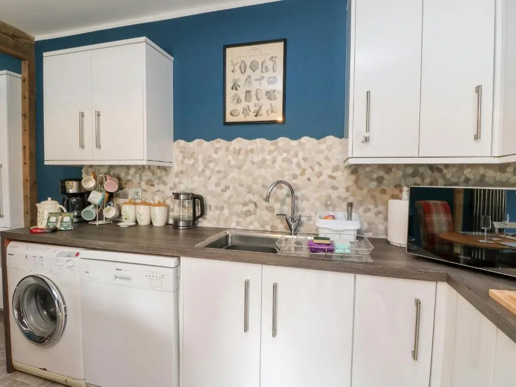 a kitchen with white cabinets and a washing machine at Ulla Dhu in Nethy Bridge