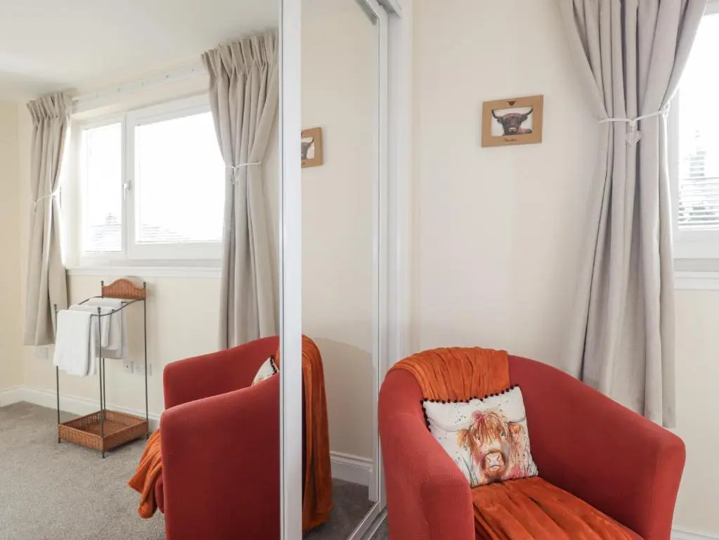 a living room with a red chair and a window at Ballinreich in Inverness