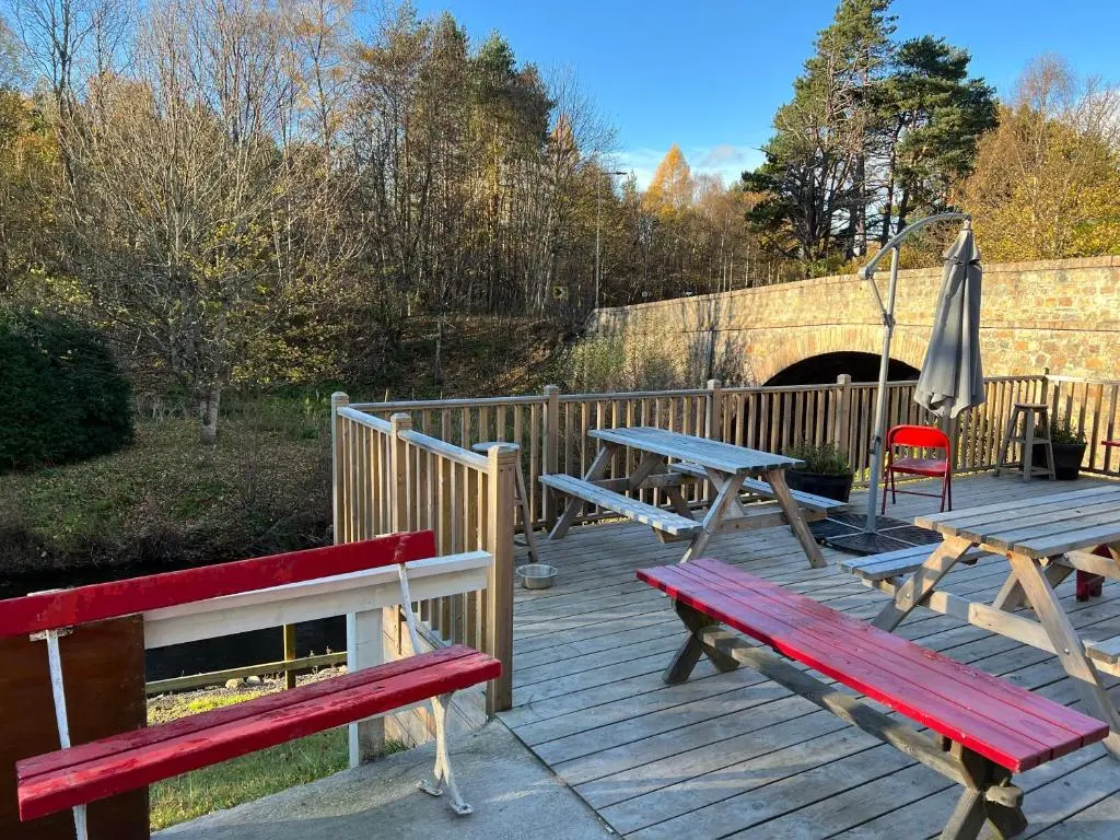 two picnic tables and an umbrella on a wooden deck at The Fiddichside Inn in Aberlour