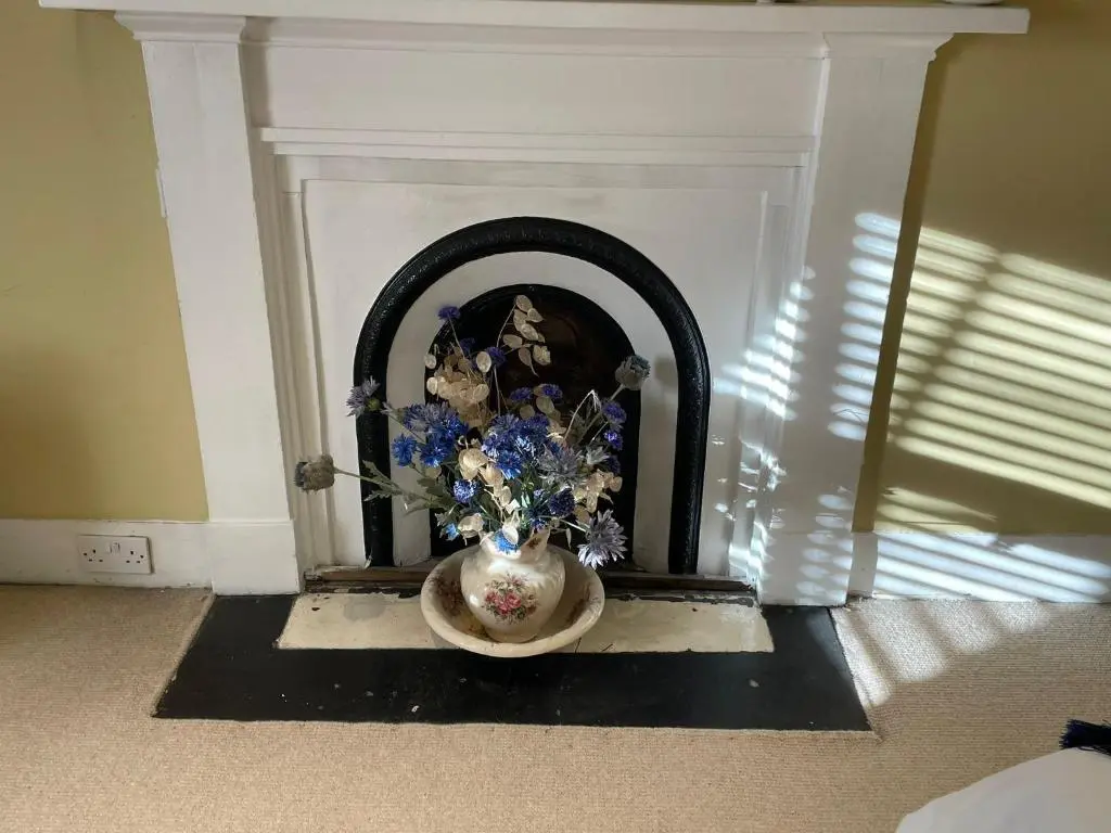 a white fireplace with a vase with flowers in it at The Fiddichside Inn in Aberlour