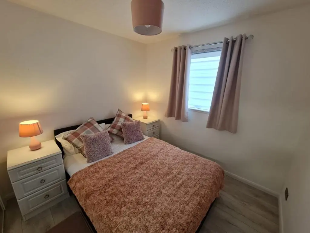 a bedroom with a bed with two lamps and a window at Lovely 2 bedroom flat in nice Inversness area. in Inverness