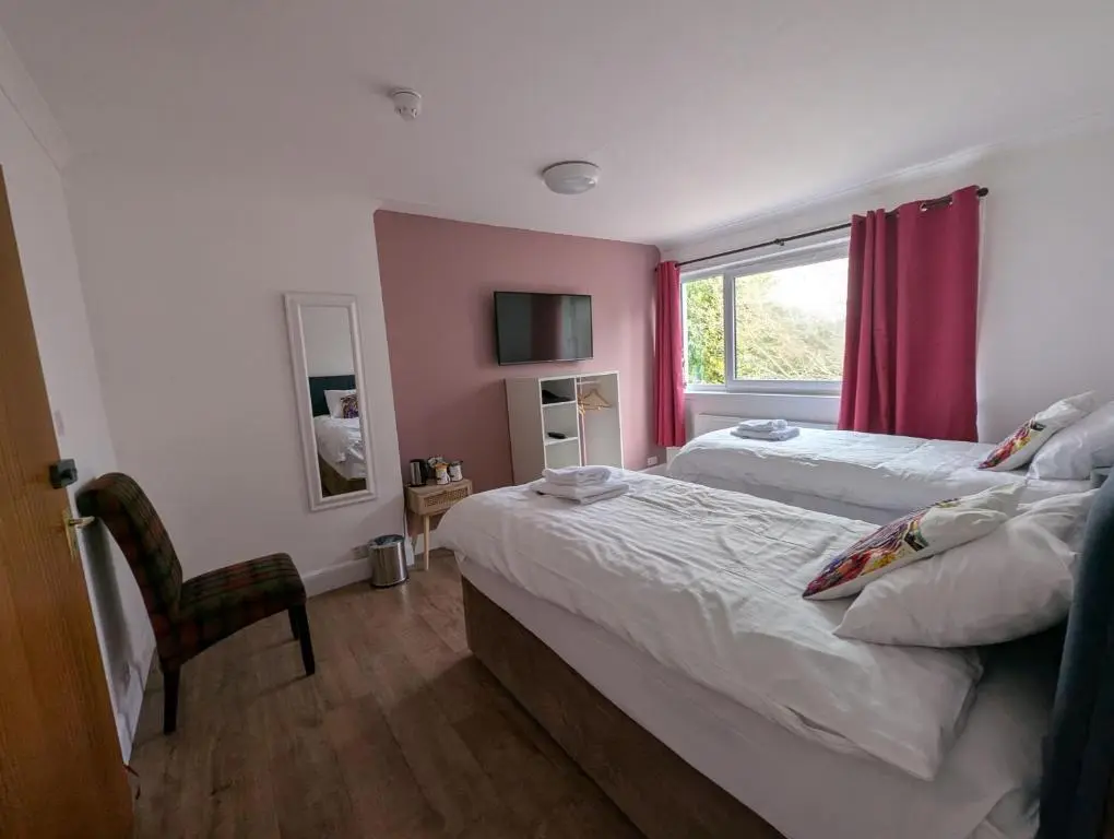 a bedroom with two beds and a chair and a window at Old North Inn Hotel in Kirkhill
