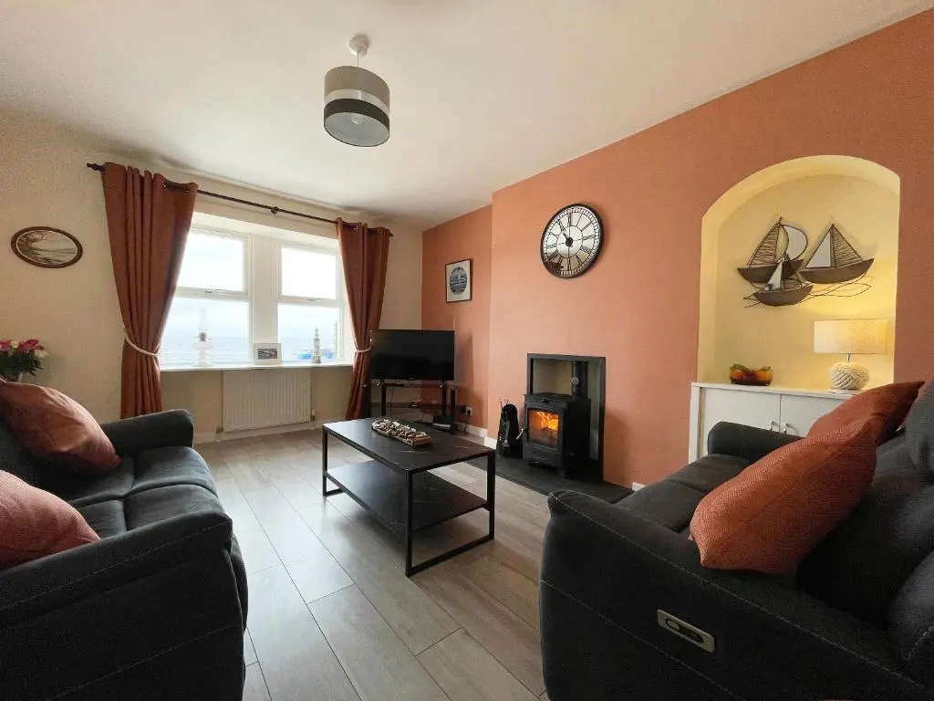 a living room with two couches and a clock on the wall at Harbour Street in Portmahomack