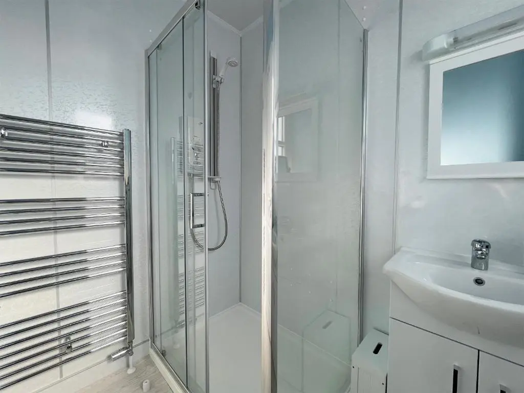 a white bathroom with a shower and a sink at Harbour Street in Portmahomack