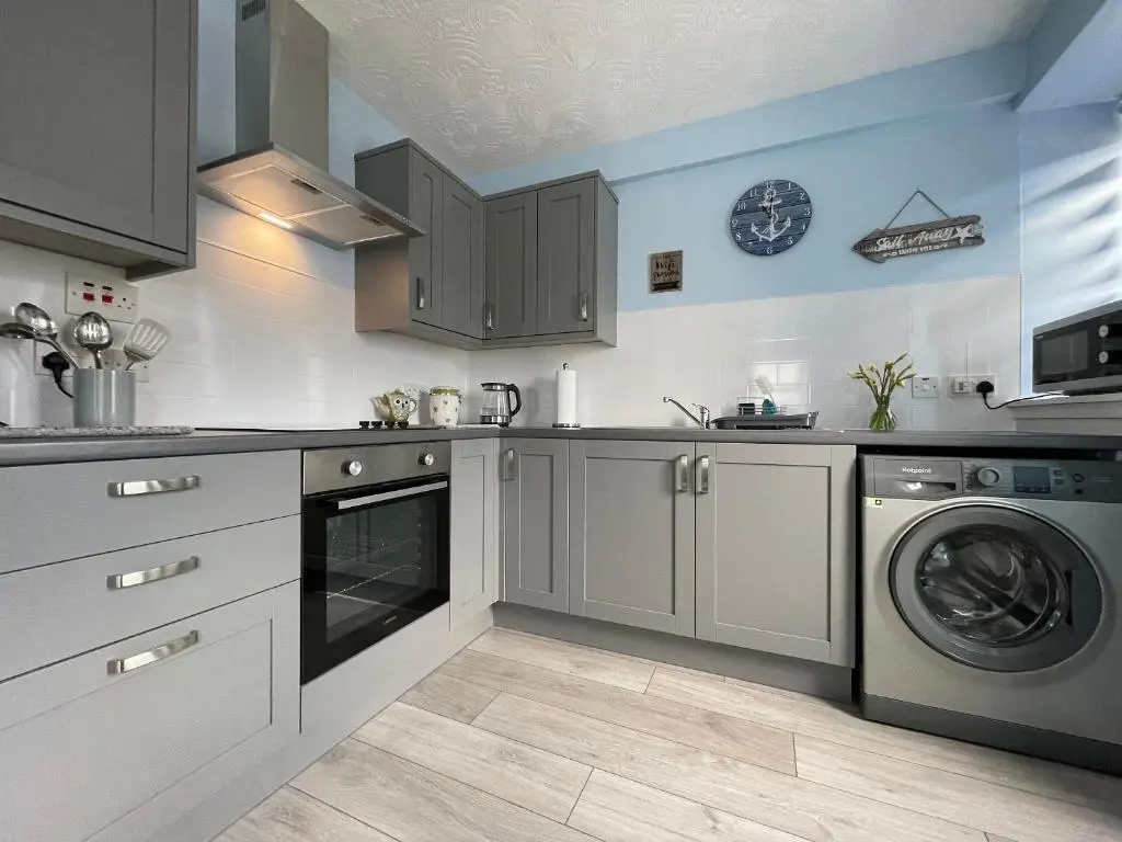 a kitchen with gray cabinets and a washer and dryer at Harbour Street in Portmahomack