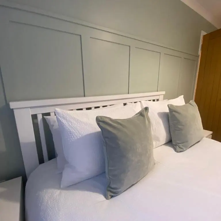 a bed with white pillows on top of it at Cathwill - Cosy 4 Star Cottage - Cairngorm National Park in Newtonmore
