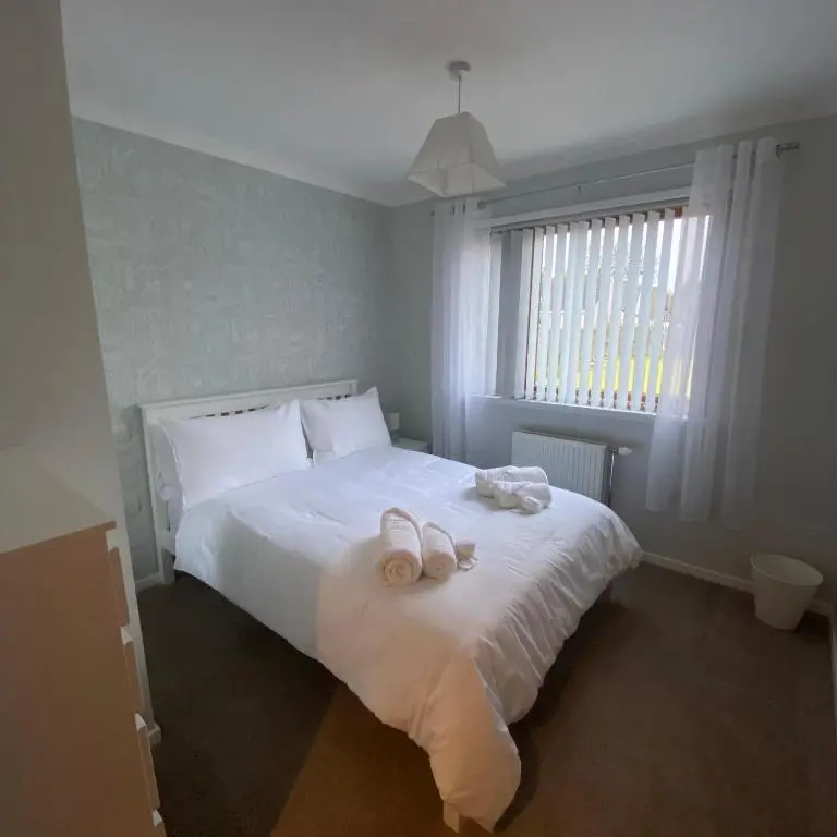 a bedroom with a white bed with two towels on it at Cathwill - Cosy 4 Star Cottage - Cairngorm National Park in Newtonmore