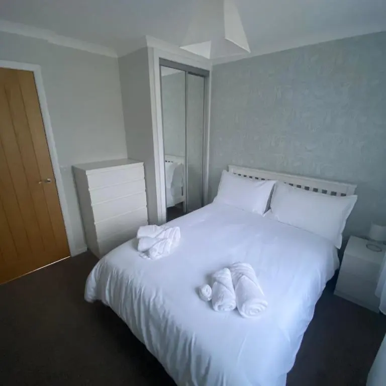 a bedroom with a white bed with towels on it at Cathwill - Cosy 4 Star Cottage - Cairngorm National Park in Newtonmore