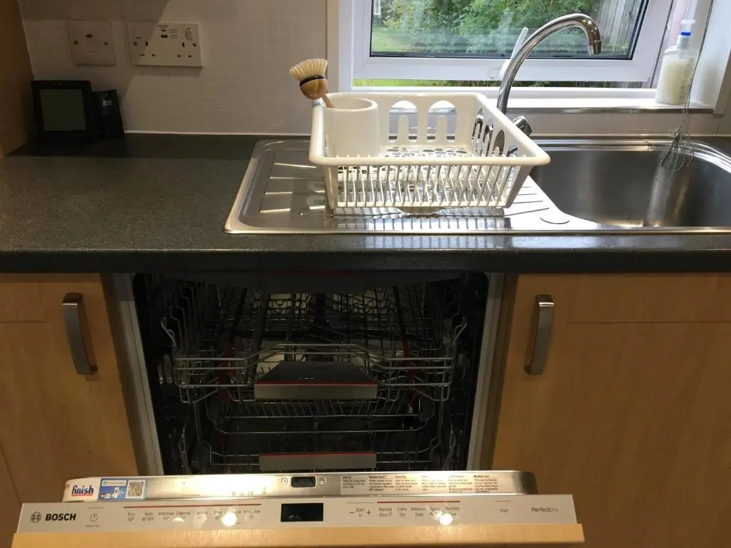 an open dishwasher in a kitchen next to a sink at Columba House in Inverness