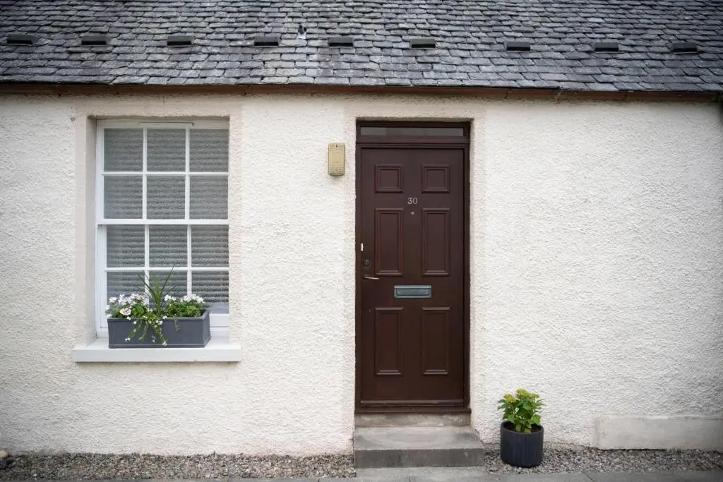 a house with a brown door and two potted plants at End House Inverness in Inverness
