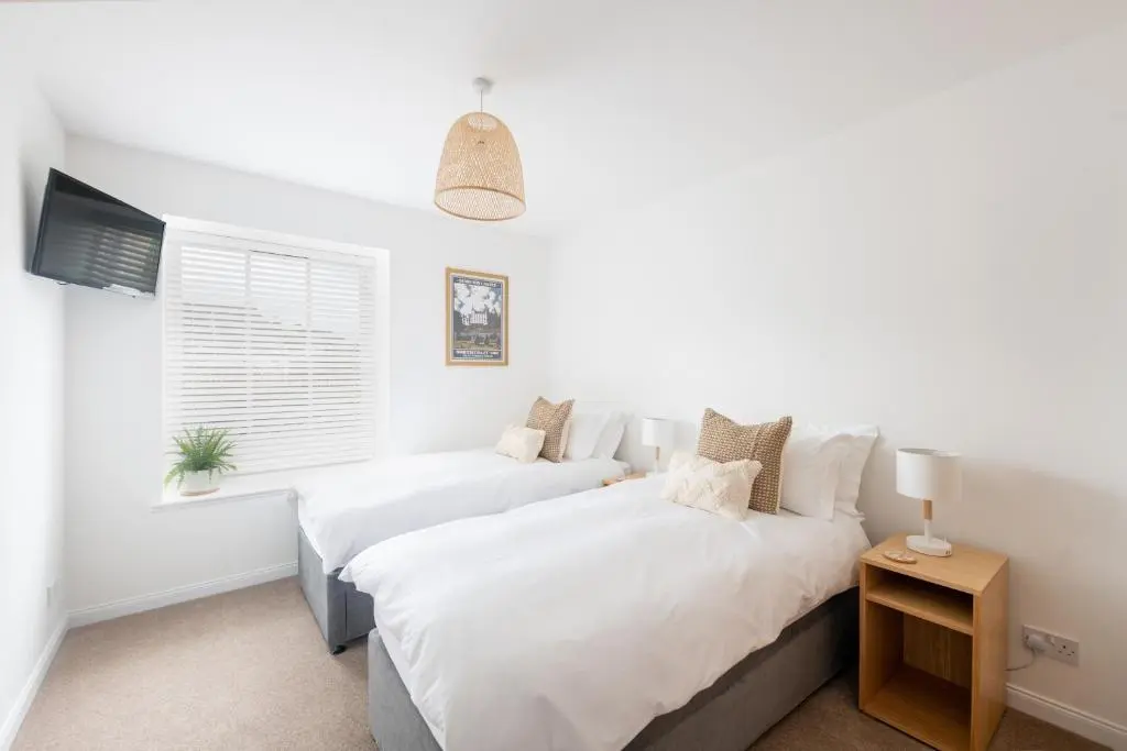 two beds in a white bedroom with a window at End House Inverness in Inverness
