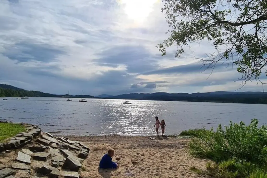 three people standing on the shore of a lake at *Cool, cosy cottage in the heart of the Highlands* in Kincraig
