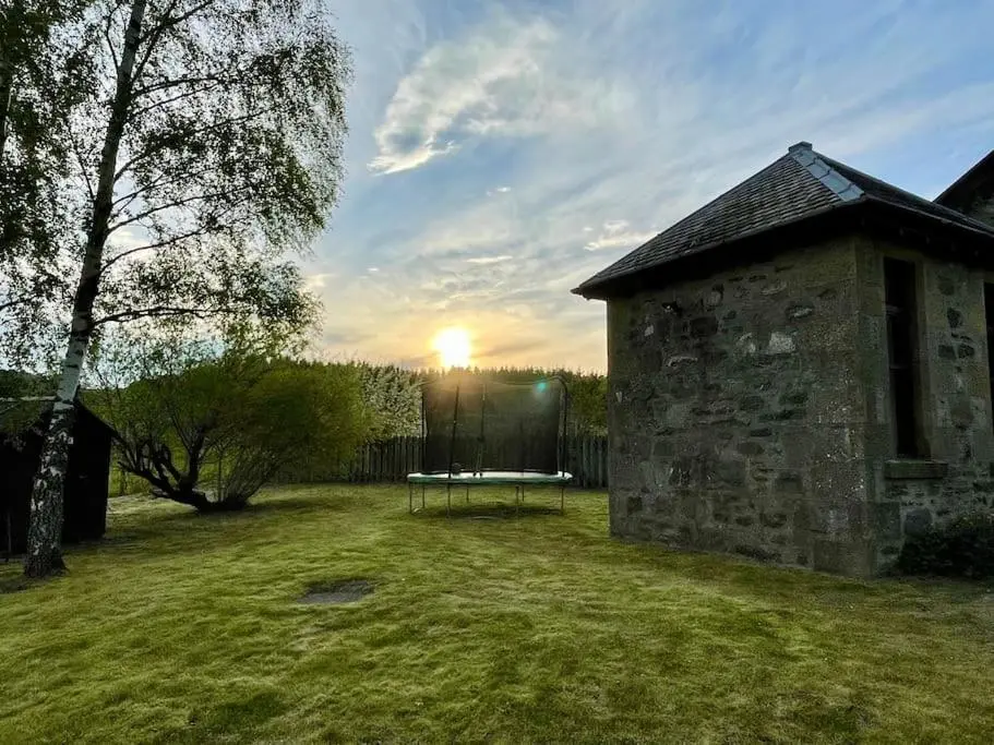 a stone building with a table in a yard at *Cool, cosy cottage in the heart of the Highlands* in Kincraig