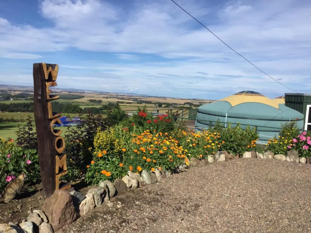 a garden with flowers and a dome in the background at Green Yurt with Hot Tub - Sleeps 3 Parking & Pets in Turriff