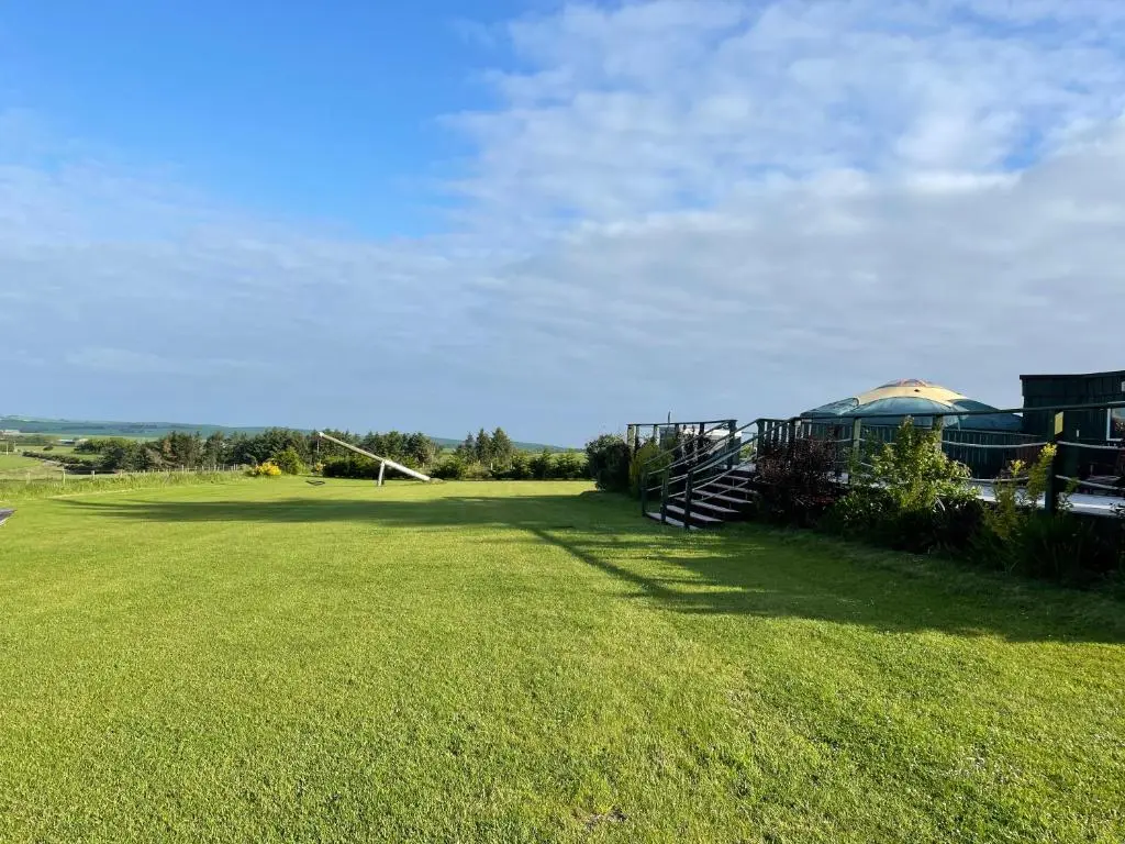 a large grassy yard with a gazebo in the distance at Green Yurt with Hot Tub - Sleeps 3 Parking & Pets in Turriff
