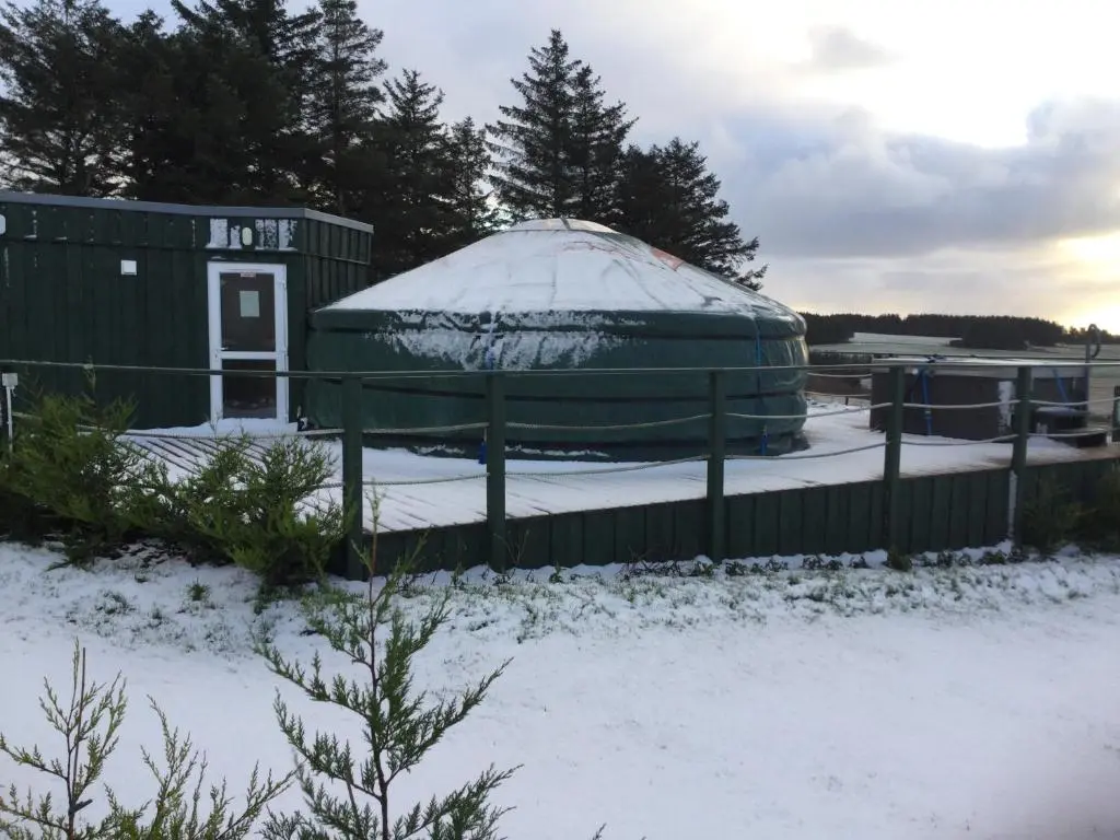a yurt is covered in snow next to a fence at Orange Yurt with Hot Tub- Sleeps 3 Parking & Pets in Turriff