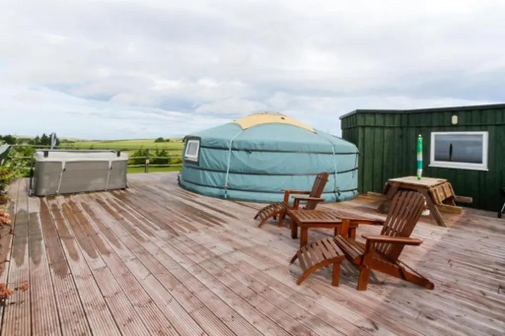 a gazebo on a deck with chairs and a table at Orange Yurt with Hot Tub- Sleeps 3 Parking & Pets in Turriff