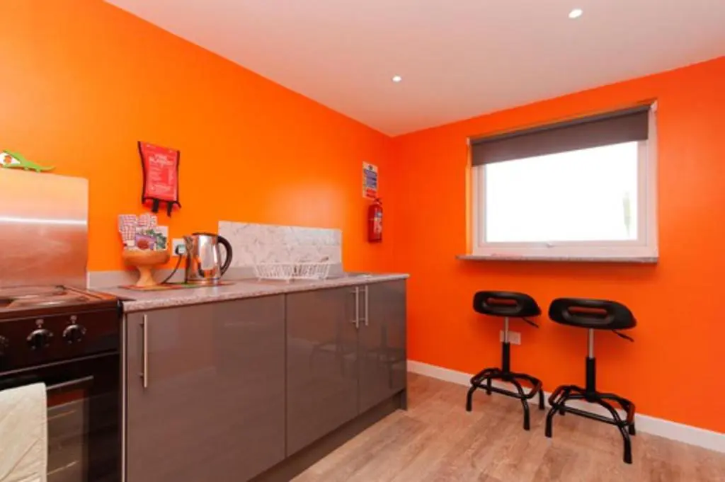 an orange kitchen with a counter and two stools at Orange Yurt with Hot Tub- Sleeps 3 Parking & Pets in Turriff