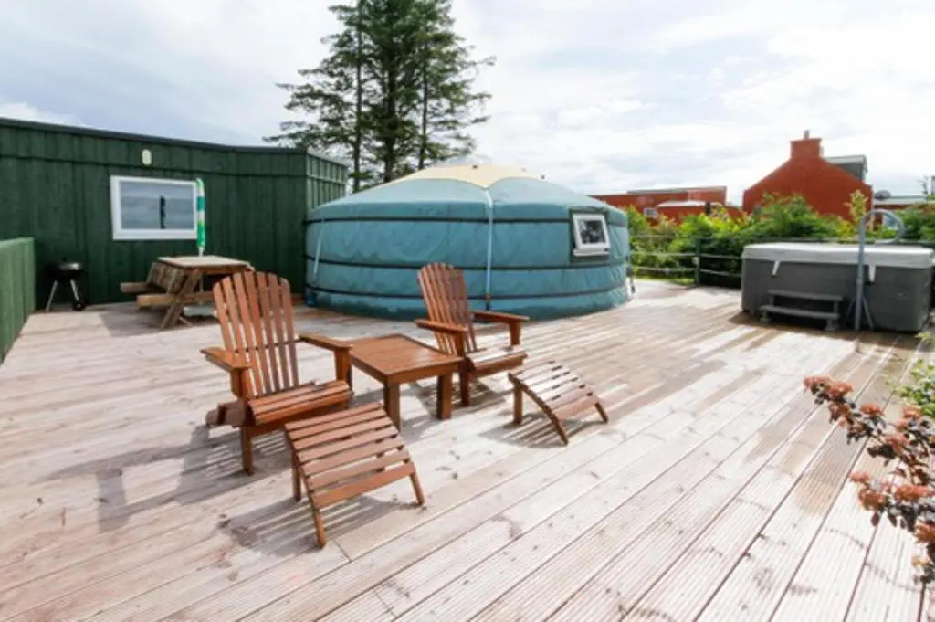 a deck with chairs and a table and a yurt at Orange Yurt with Hot Tub- Sleeps 3 Parking & Pets in Turriff