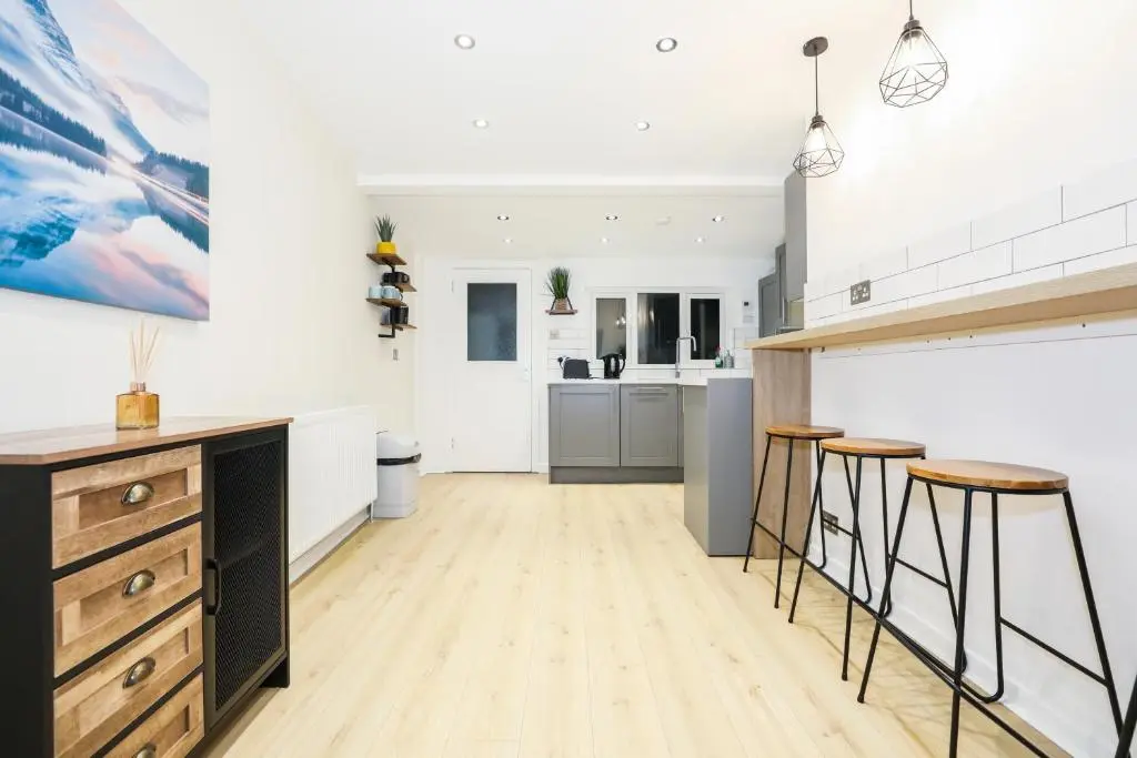 a kitchen with a counter and stools in a room at mySTAYINN Tomnahurich 3 Bedroom House in Inverness