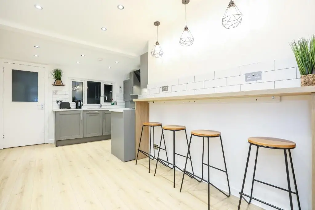 a kitchen with bar stools and a counter top at mySTAYINN Tomnahurich 3 Bedroom House in Inverness
