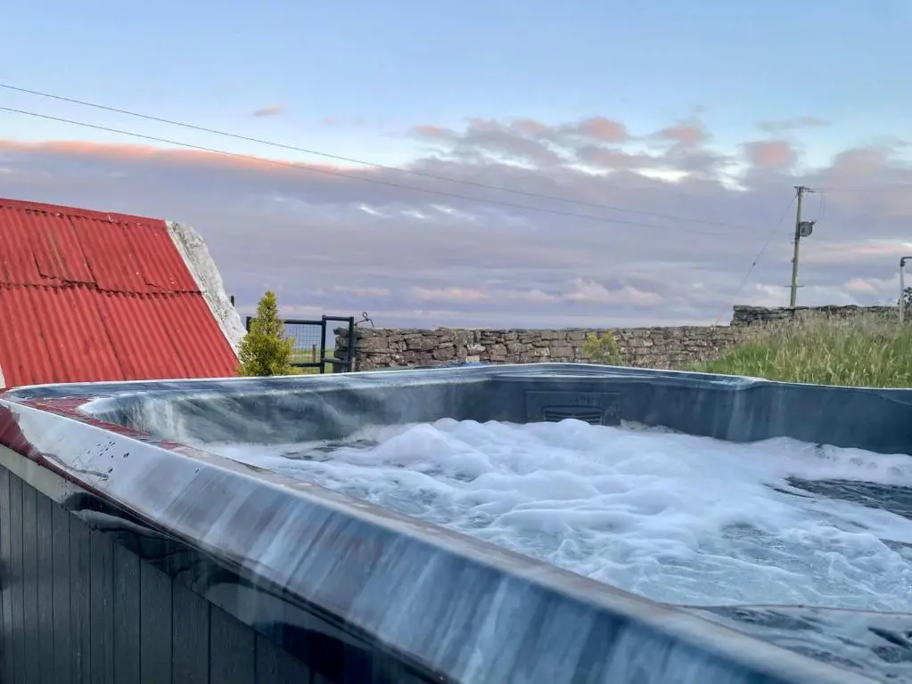 a hot tub filled with water next to a building at Ceol na Mara in Berriedale