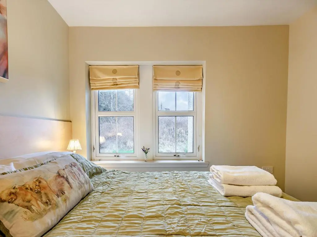a bedroom with a large bed with two windows at Allt Na Criche - Ukc5762 in Laggan