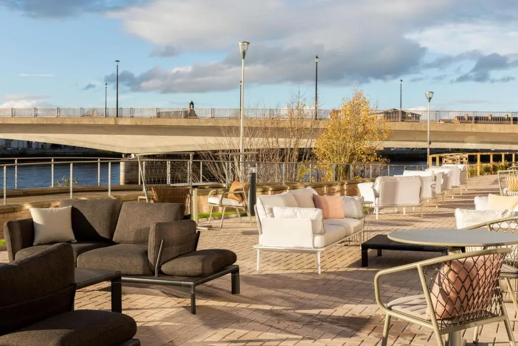 a patio with chairs and tables and a bridge at AC Hotel by Marriott Inverness in Inverness