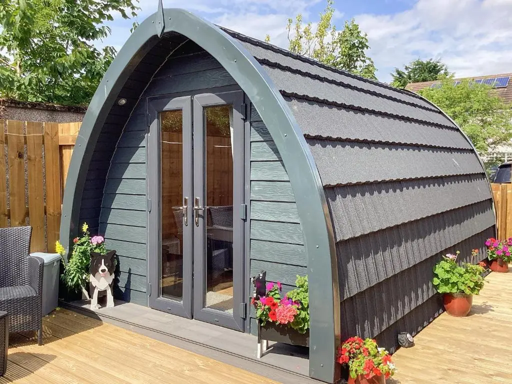 a dog is sitting in a blue shed at The Dalmore Pod in Alness