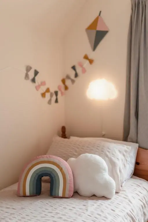 a childs bedroom with a rainbow pillow on a bed at Balnagowan Cottage in Nethy Bridge
