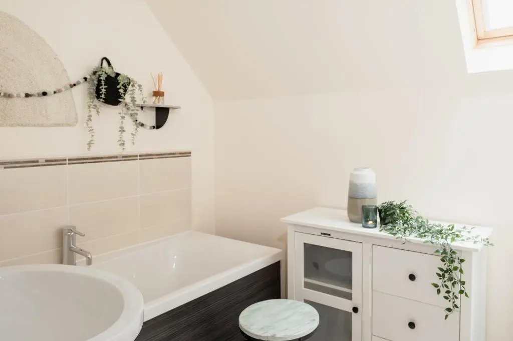 a bathroom with a white tub and a sink at Balnagowan Cottage in Nethy Bridge
