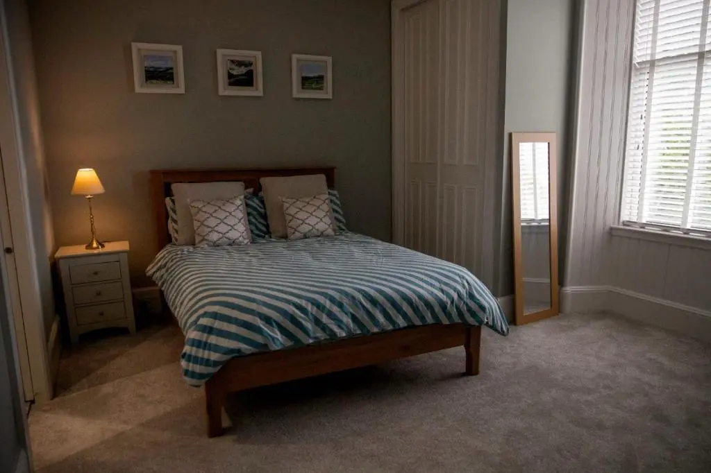 a bedroom with a bed and a lamp and a window at The old church house in Inverness