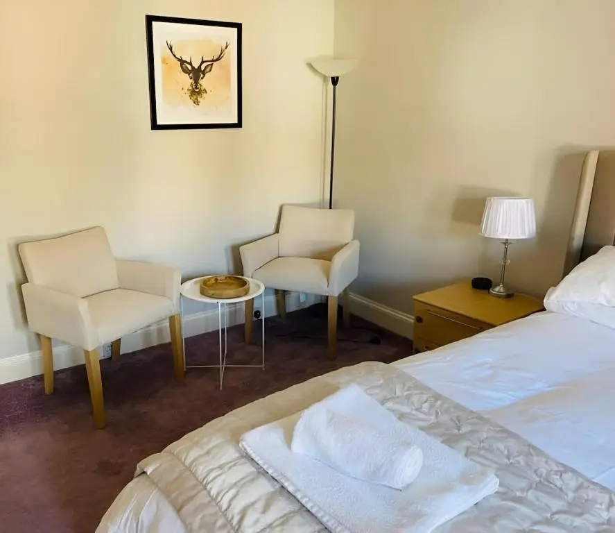 a bedroom with a bed and two chairs and a lamp at Ashley House Contemporary 4 Bedroom Stay for 13 in Inverness