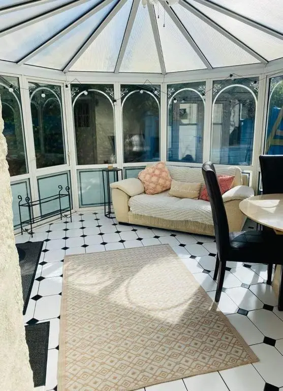 a conservatory with a couch and a table and chairs at Ashley House Contemporary 4 Bedroom Stay for 13 in Inverness