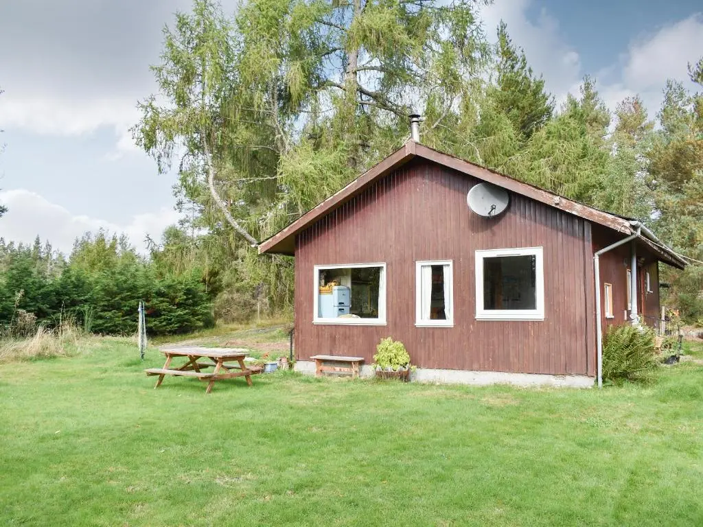 a small red cabin with a picnic table in the yard at The Chalet - Ukc5786 in Nethy Bridge