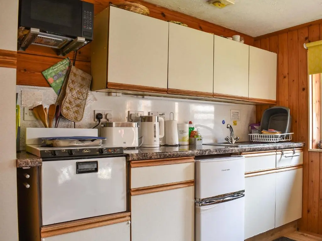 a kitchen with white appliances and wooden cabinets at The Bothy - Ukc5785 in Nethy Bridge
