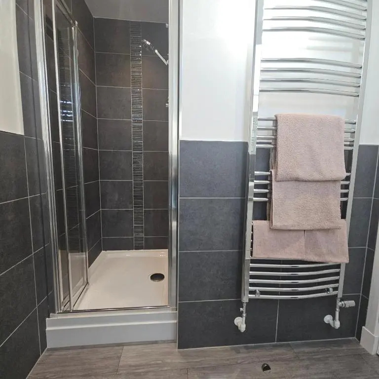 a bathroom with a shower with towels and a sink at The White House in Elgin