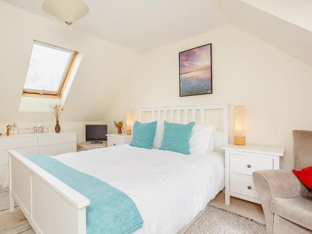 a bedroom with a large white bed with blue pillows at Caldon Cottage in Cromarty