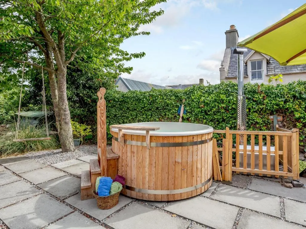 a wooden hot tub sitting on a patio at Caldon Cottage in Cromarty