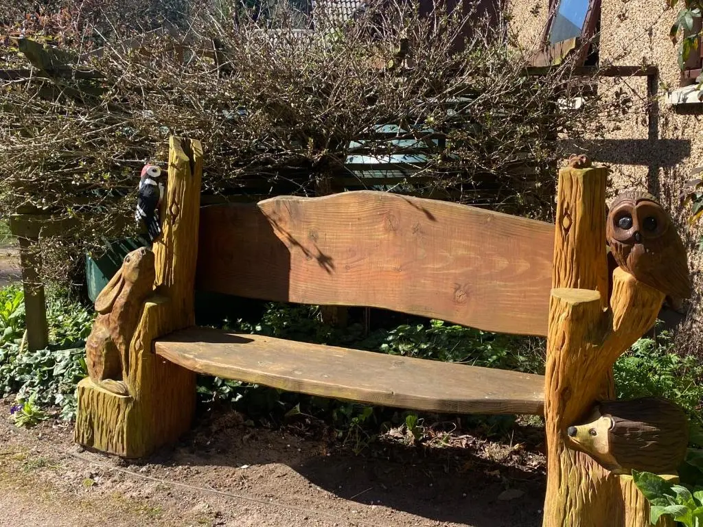 a wooden bench with two faces on it at Drummond Neuk - Pets Welcome free, country setting, free onsite parking in Inverness