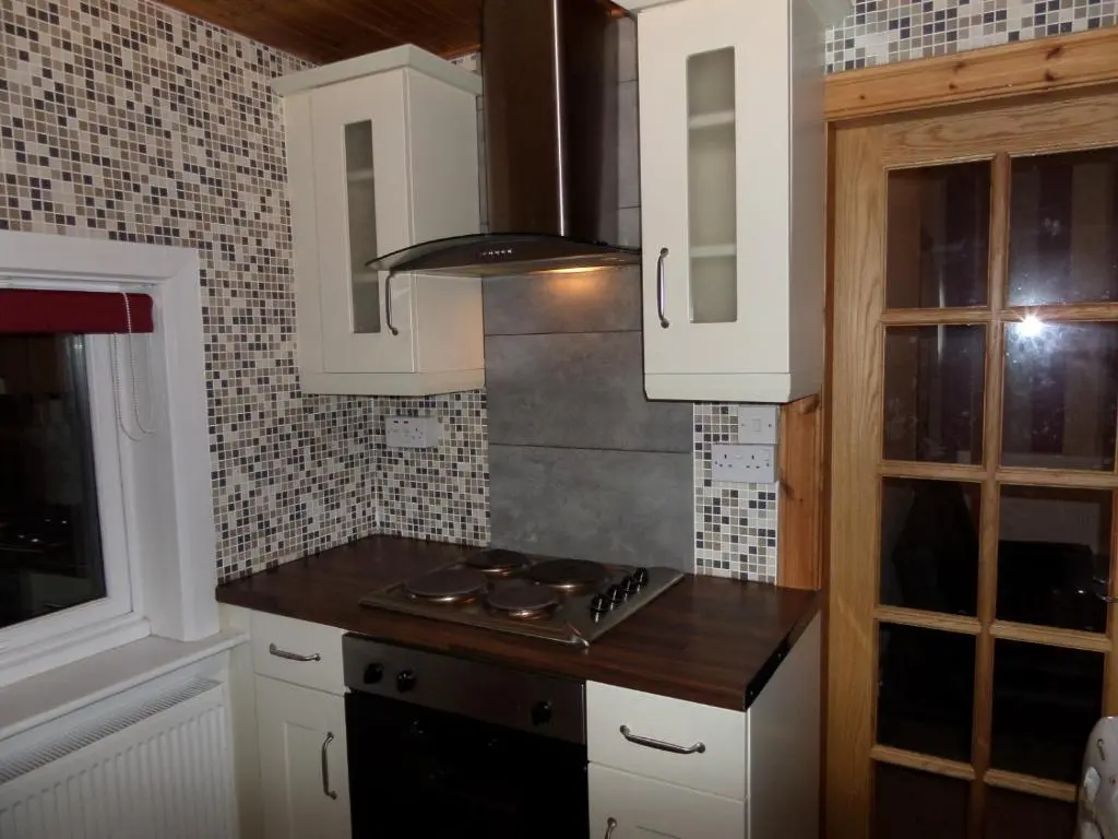 a kitchen with white cabinets and a stove top oven at Jane's Cottage Free Parking in Inverness